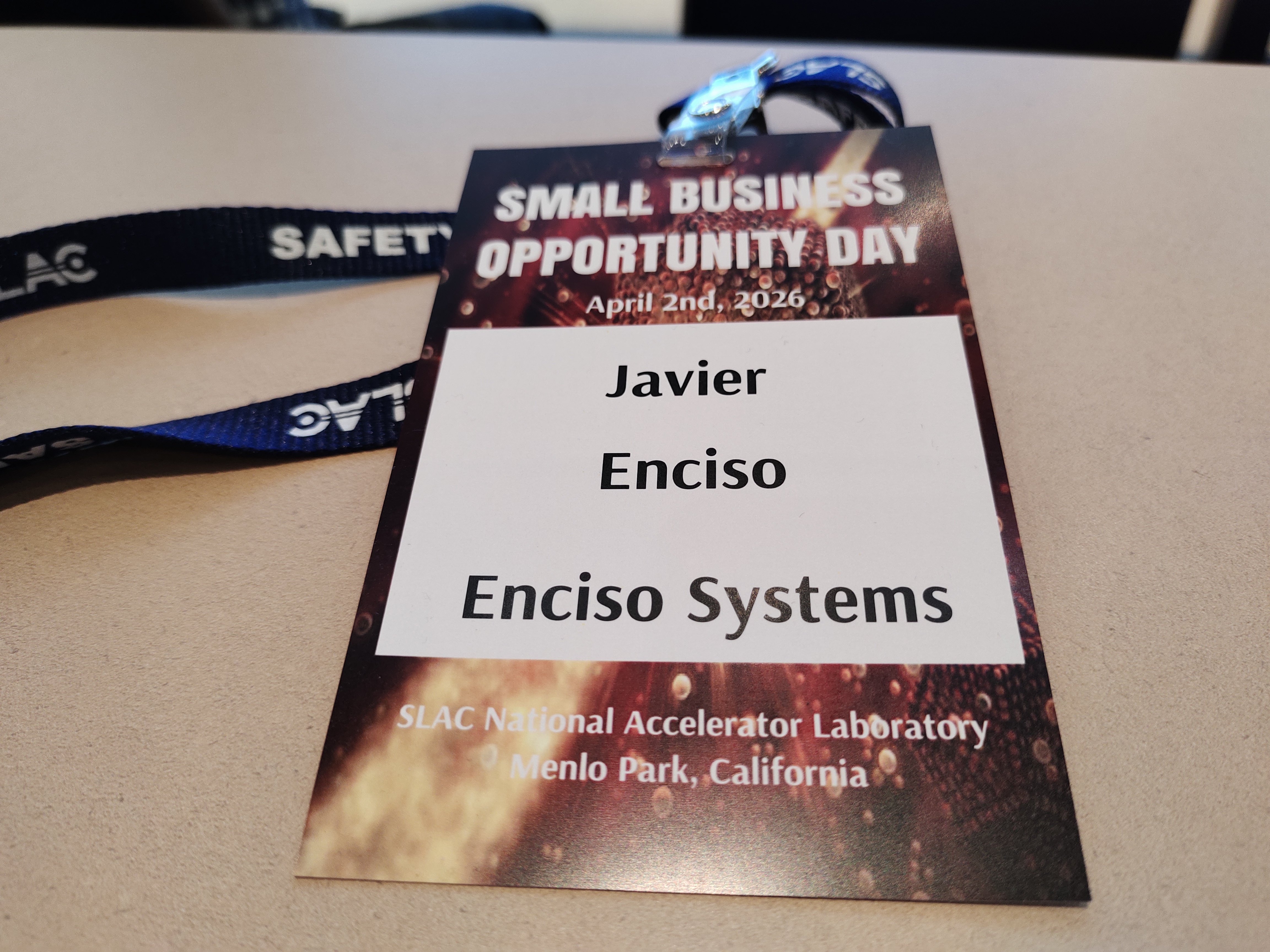A close-up view of Javier Enciso's name badge for Enciso Systems, attending the Small Business Opportunity Day on April 2nd, 2026, at SLAC National Accelerator Laboratory in Menlo Park, California.